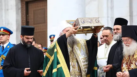 Pravoslavni svećenici u liturgijskim odjevima drže zlatni kovčeg