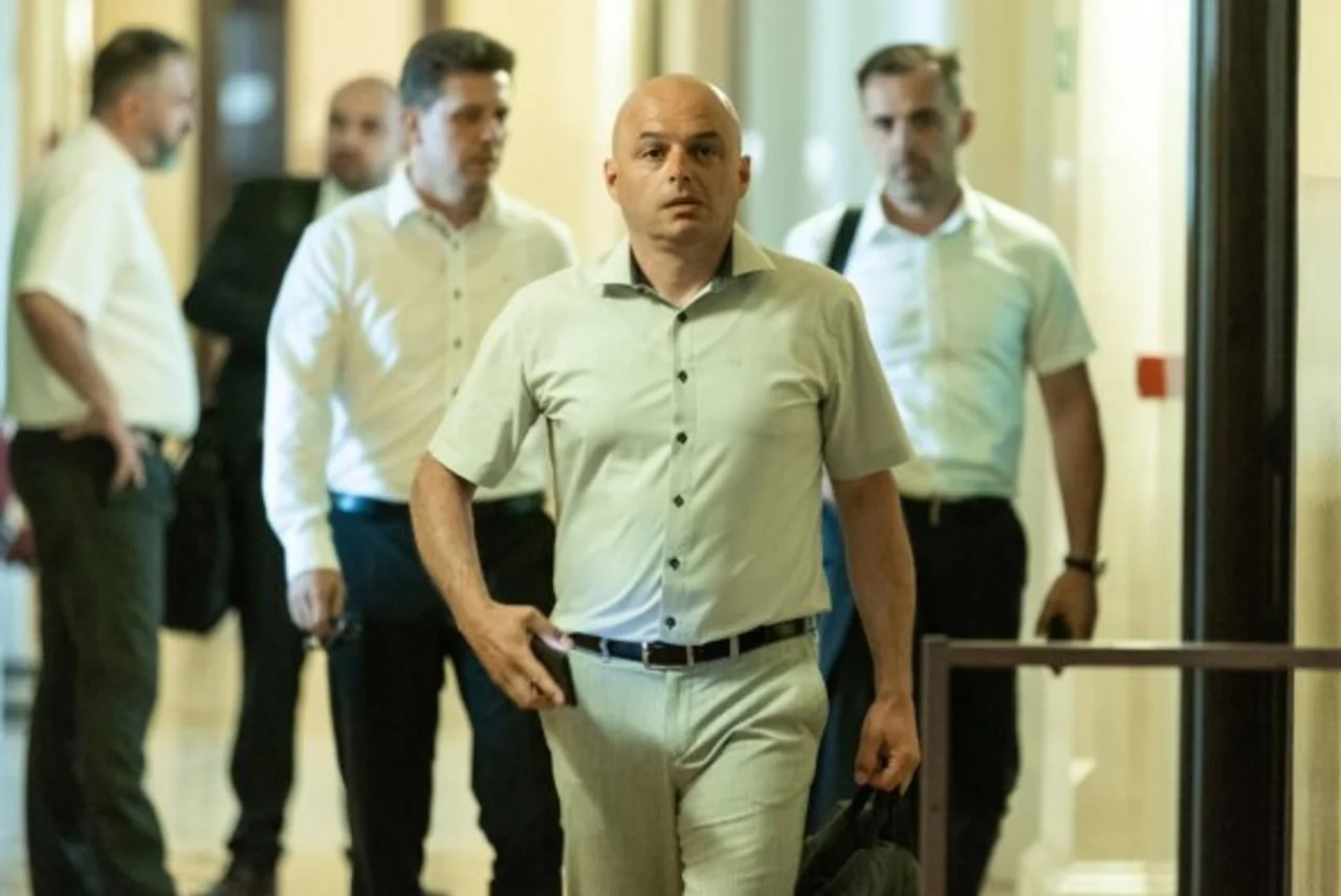 Muškarac u svijetloj košulji hoda hodnikom u pratnji