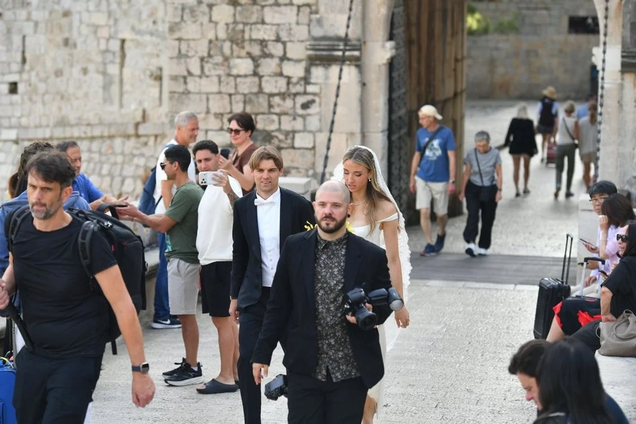 Par u vjenčanim odjevima u pratnji fotografa kroz grad
