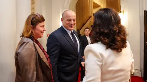 Muškarac u tamnom odijelu razgovara s dvije žene u elegantnom interijeru