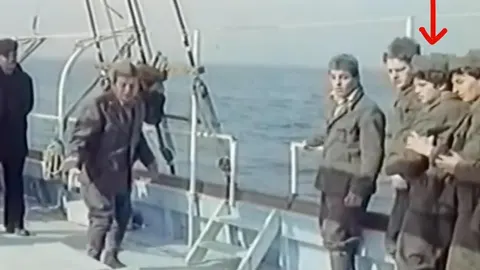 Grupa mladih ljudi u zimnim kaputima na palubi broda