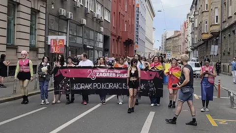 Grupa ljudi nosi ljubičasti transparent Zagreb Pride ulicama grada