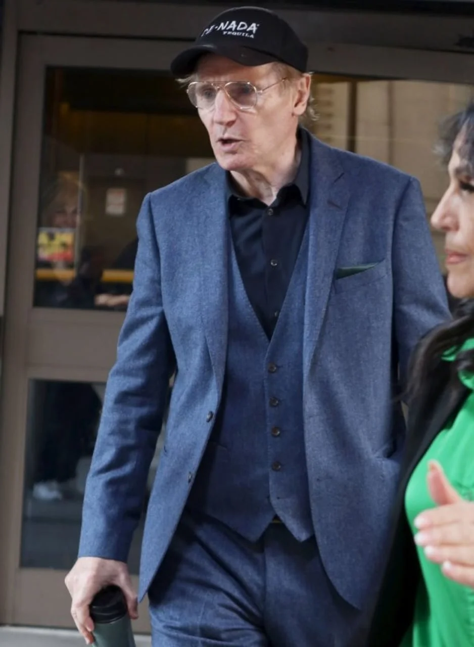Liam Neeson u plavom trodielnom odelu, crnom kapu i naočalama
