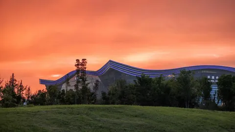 Moderna zgrada New Century Global Center s zakrivljenim krovom u sutonu