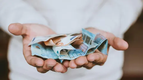 Dvoje ruku koje drže gomilu novčanica u eurima
