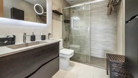 Moderna kupaonica s bijelim sanitarijema i staklenim tuš kabinom