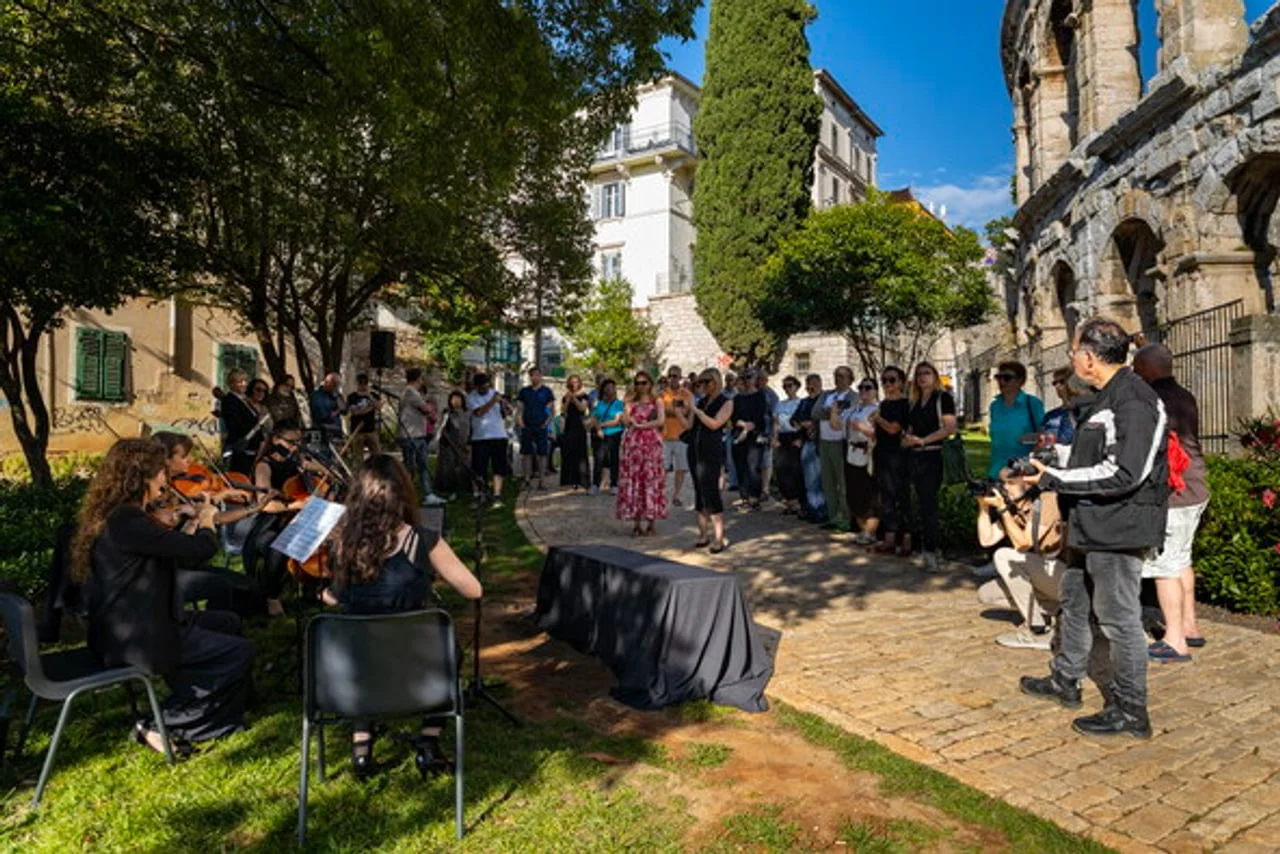 Grupa ljudi i glazbenici na otvorenom pored Arene