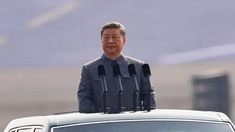 Kineski predsjednik Xi Jinping stoji za govornicom s četiri mikrofona.