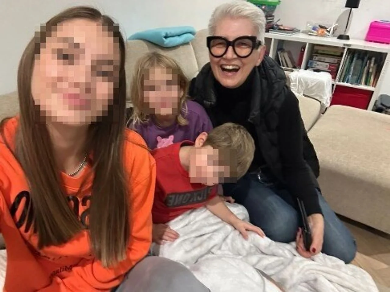 Žena s naočalama i troje djece s zamagljenim licima na kauču
