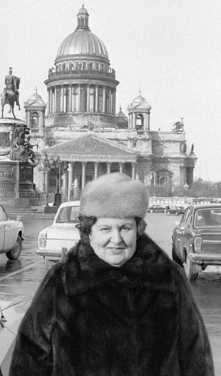 Žena u zimskom kaputu i šeširu ispred velike crkve s kupolom