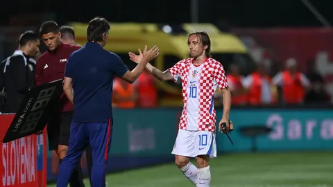 Luka Modrić u crveno-bijelom dresu Hrvatska rukuje s trenerom na terenu