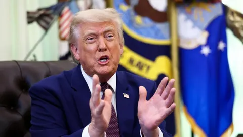 Donald Trump u tamnoplavom odelu i crvenoj kravati gestikulira rukama