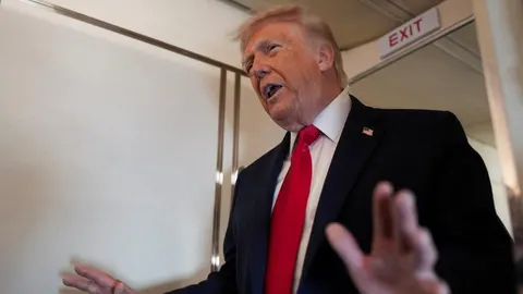 Donald Trump u tamnom odelu i crvenoj kravati gestikulira rukama