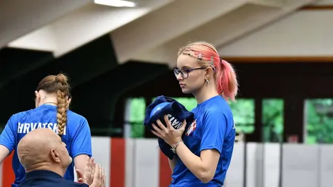 Mlada sportašica u plavom dresu s naočalama drži plavu loptu
