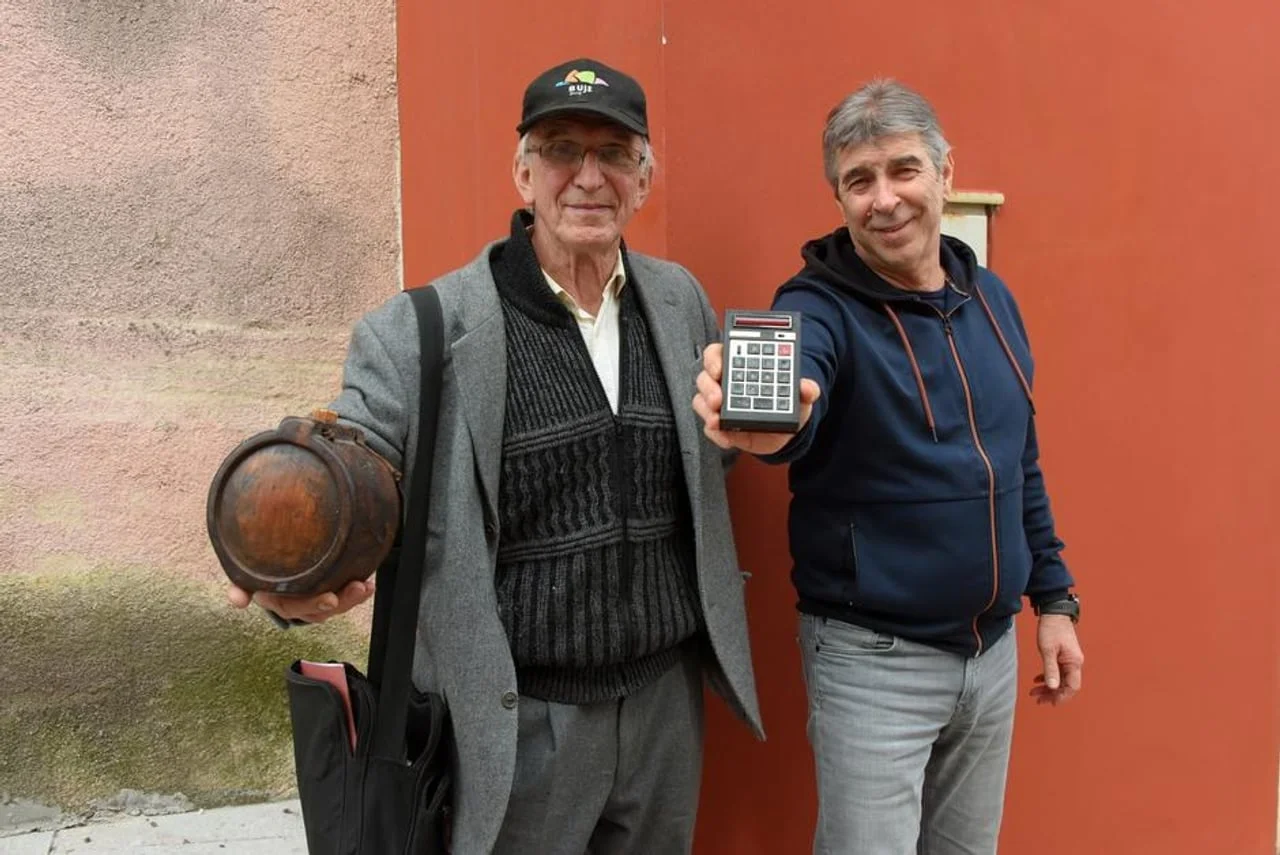 Dvojica muškaraca drže drvenu posudu i starinski digitalni kalkulator.
