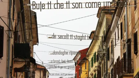 Ulica u Bujama sa stihovima ispisanim na žicama iznad ceste.