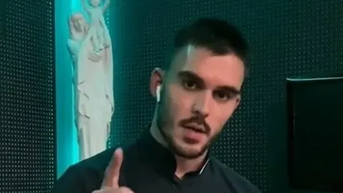 Don Tomislav Lukač u crnom odjeću s podignutim prstom u pozadini religijske statue