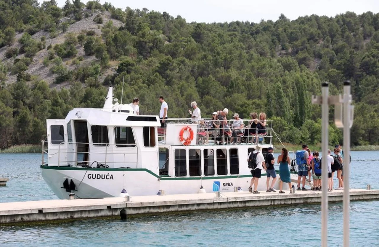 Brod Guduća na pristaništu s putnicima ispred šume