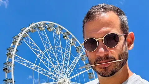 Portret pjevača Borisa Rogoznice s narančastim okvirem naočala ispred velikog kotača