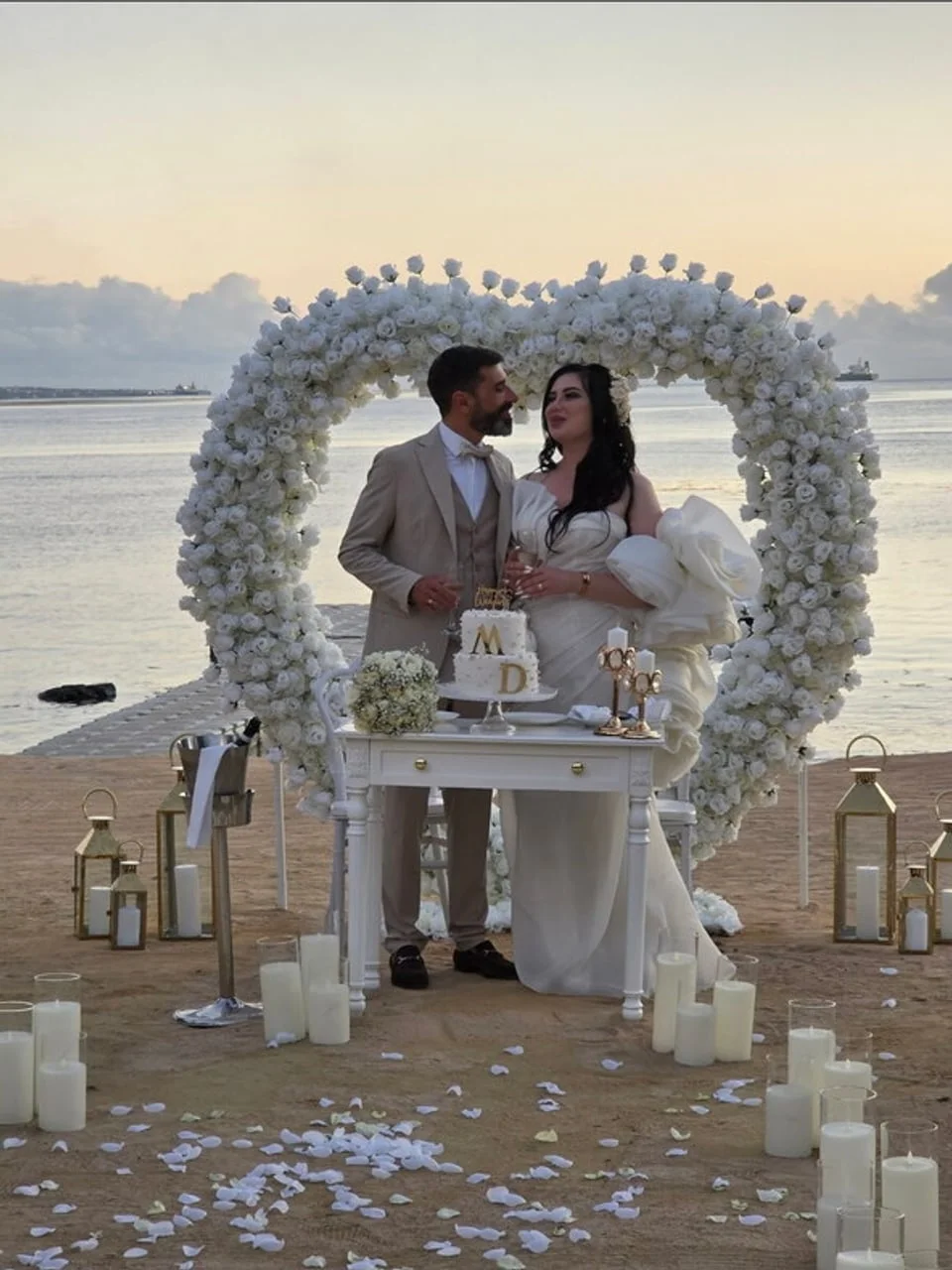 Mladenac i mladenca pored vjenčane torte na plaži u suton