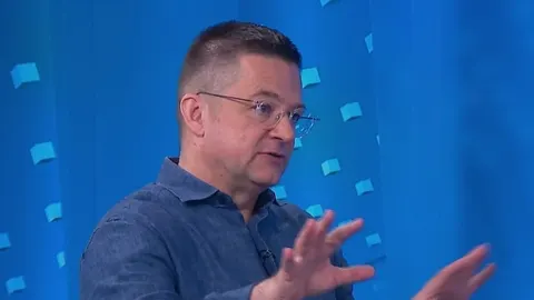 Muškarac s naočalama u plavoj košulji gestikulira rukama