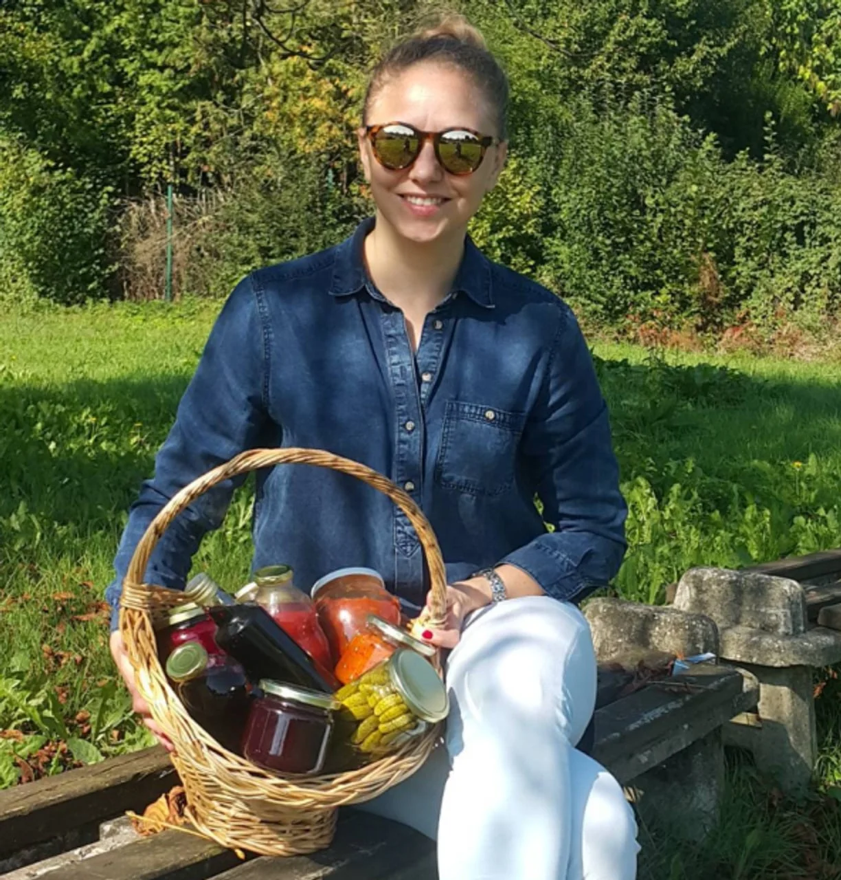 Nasmijana žena s košarom punom staklenki domaćih zimnica
