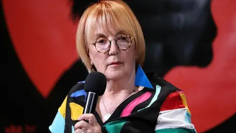 Portret Vedrane Rudan s mikrofonom u ruci i šarenom sakoom