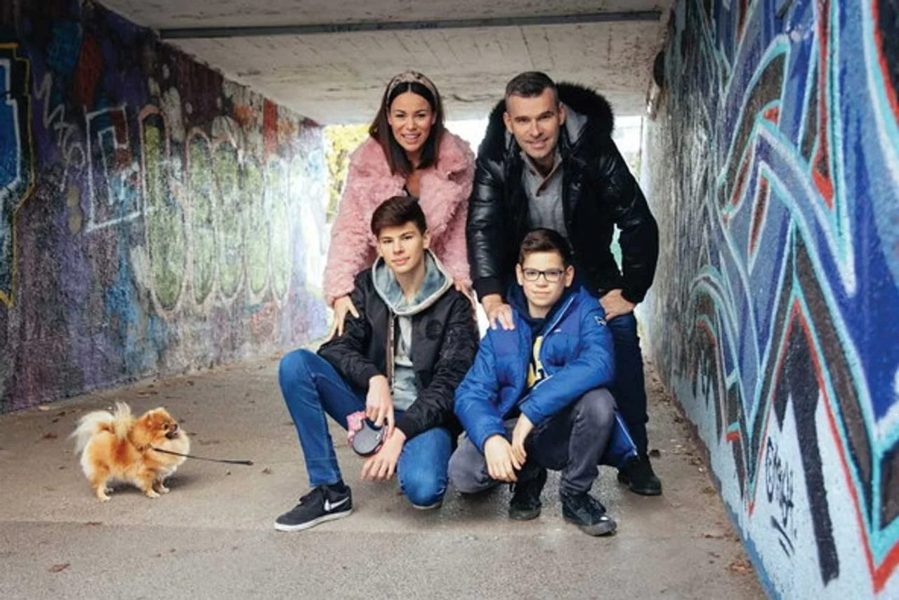 Obitelj s četvero članova i malim psom u prolazu s grafitima