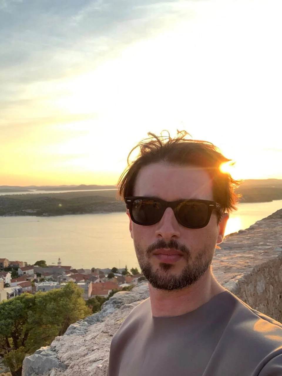 Selfie muškarca s tamnim naočalama na vidiku iznad grada i mora