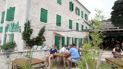 Vanjski dio restorana s kamenim zidovima i zelenim kapcima