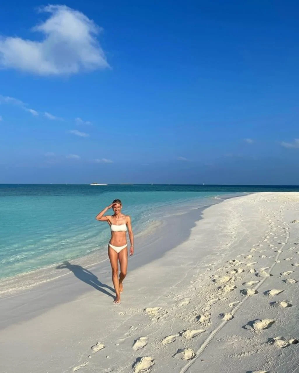 Michelle Hunziker u bijelom kupaćem hoda uz obalu tirkiznog mora