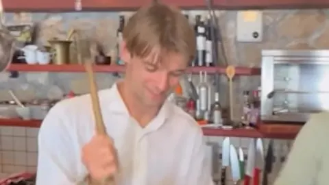 Borna Sosa u bijeloj košulji miješa nešto u kuhinji