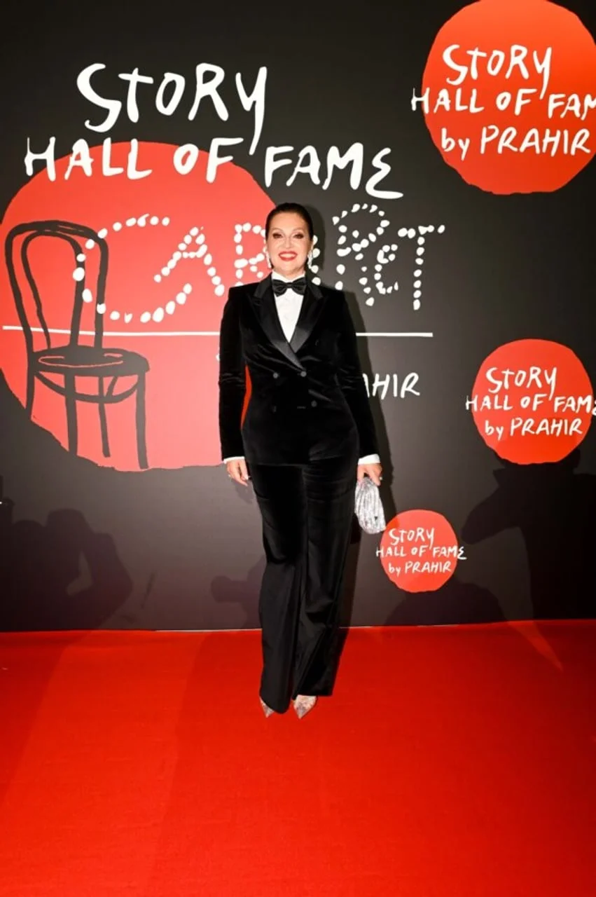 Nina Badrić u crnom ženskom smookingu ispred Story Hall of Fame zida