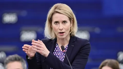Portret Kaje Kallas u tamnom saku dok govori za govornikom
