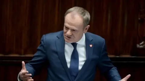 Donald Tusk u tamnoplavom odelu govori s gestikulacijom ruku