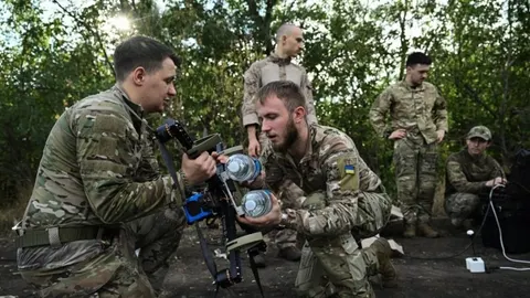 Grupa vojnika u kamuflažnoj odjeći pregledava vojni dron u šumi