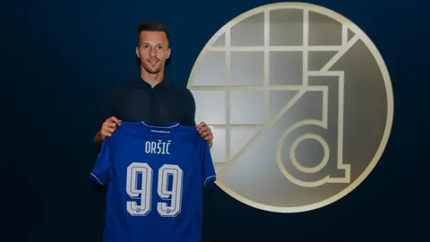 Mislav Oršić drži plavi nogometni dres Dinama s brojem 99