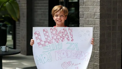 Dječak koji drži veliki plakat s natpisom Luka za moj rođendan