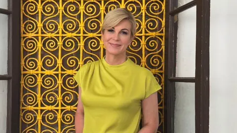 Portret Kolinde Grabar-Kitarović u žutoj majici ispred žute rešetke