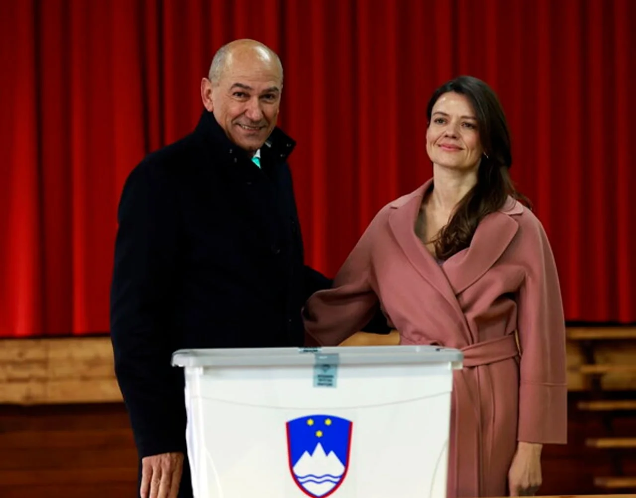 Janez Janša i Urška u ružičastom kaputu stoje pored izborne kutije