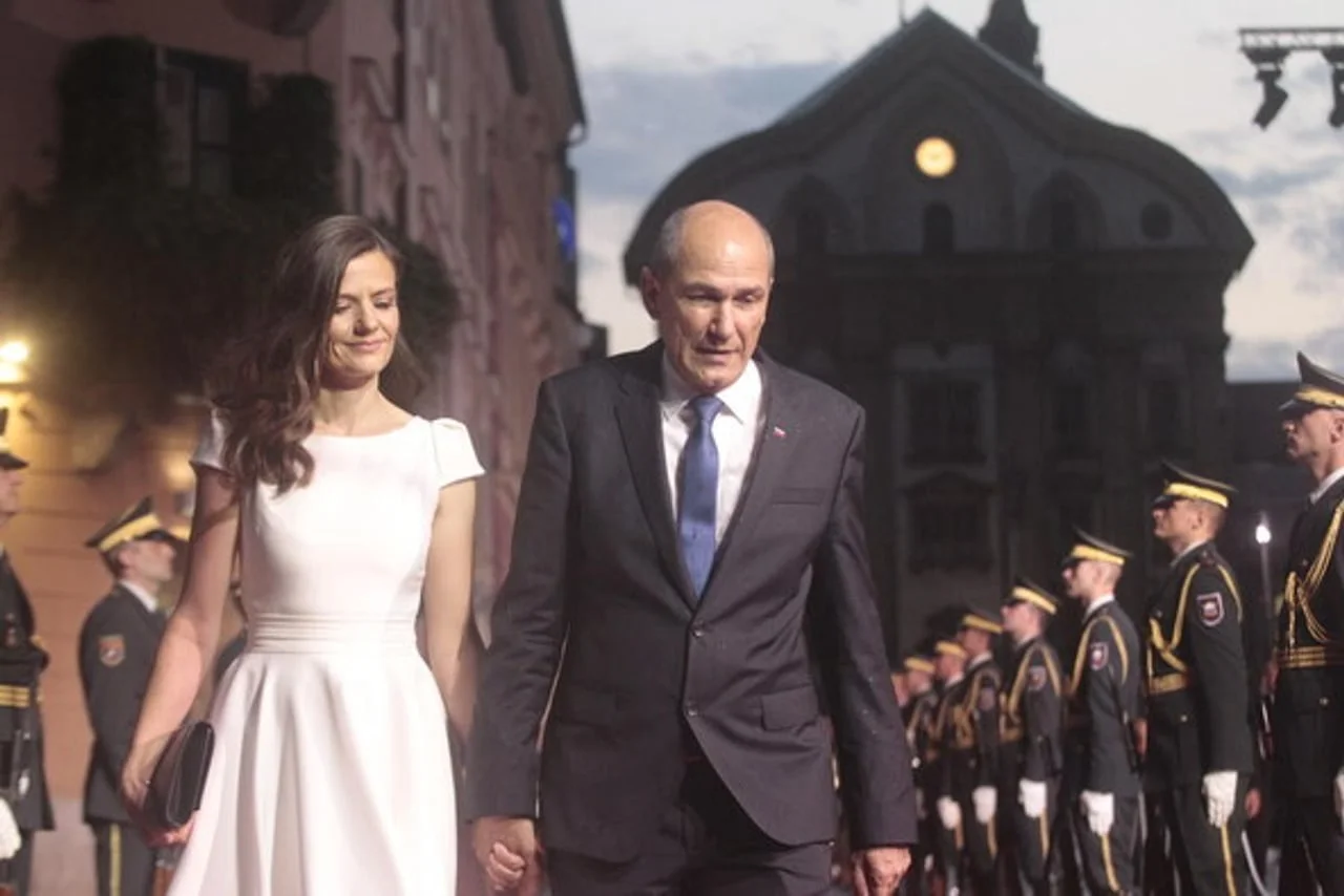 Janez Janša u odelu i Urška u bijeloj haljini hodaju pored vojnika