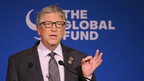Bill Gates u odelju i s naočalama govori za govornicom