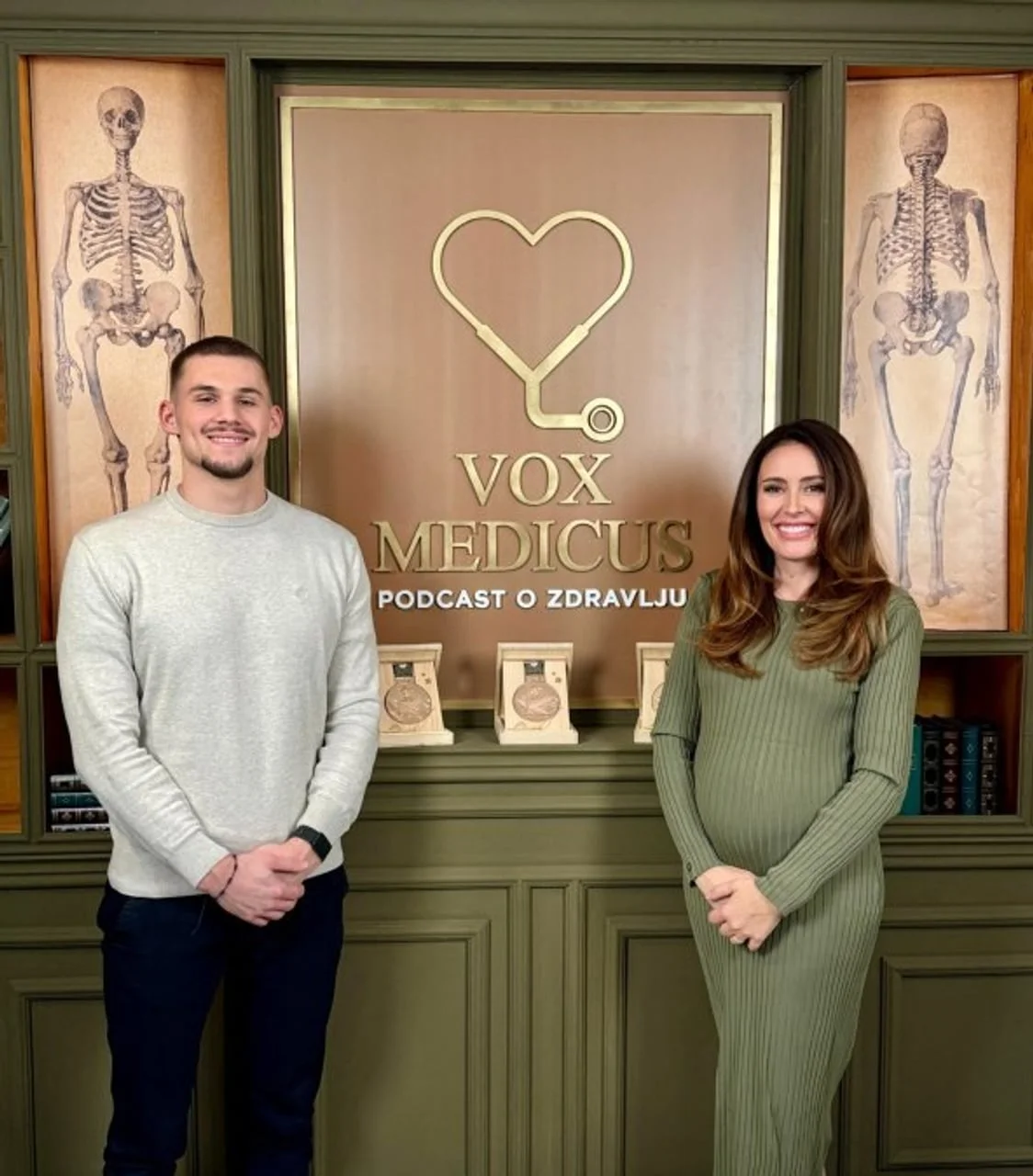 Nikola Zdrilić i voditeljica u studiju ispred zidnih ilustracija skeleta