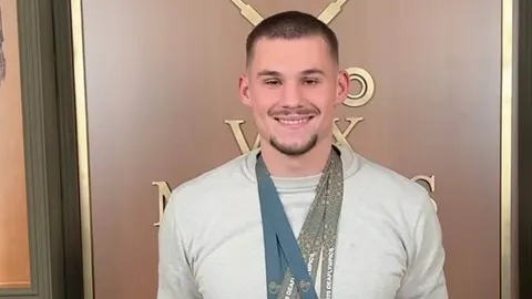 Portret Nikole Zdrilića u svijetlom dresu s medaljama oko vrata