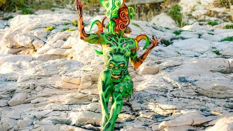 Osoba s bodypaintingom u zelenim tonovima na svijetlim stjenama