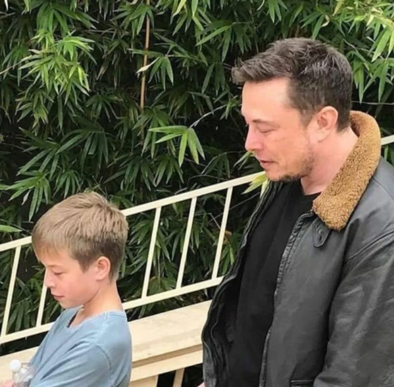 Elon Musk u crnoj kožnoj jakni stoji pored dječaka