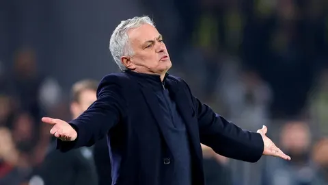 Jose Mourinho u tamnom saku s raširenim rukama i ozbiljnim izrazom lica