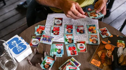 Ruke kolekcionara koji slaže Panini sličice nogometaša na stolu