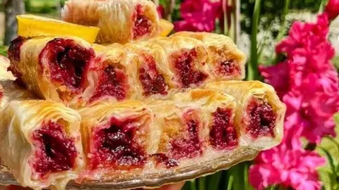 Slojevite komade posne pite punjene crvenim višnjama na staklenom tanjuru