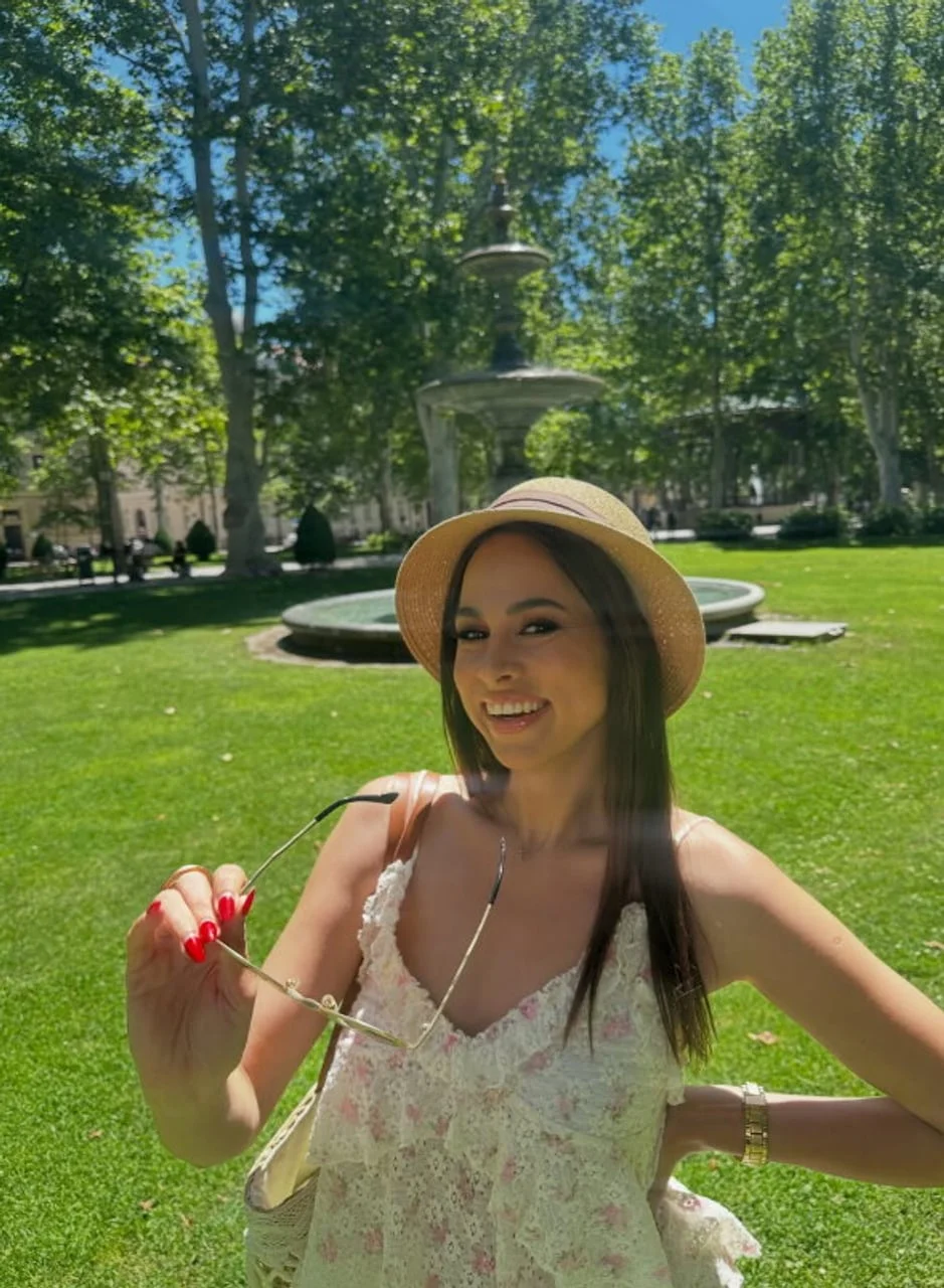 Mlada žena s pletenim šeširom i sunčanim naočalama u parku
